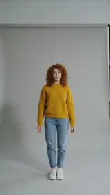 Das Foto für dieses Beispiel: eine Frau mit roten Locken und gelbem Pullover steht in einem grauen Fotostudio
