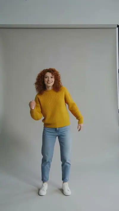 Beispiel Foto zu Video KI: eine Frau mit roten Locken und gelbem Pullover tanzt in einem grauen Fotostudio